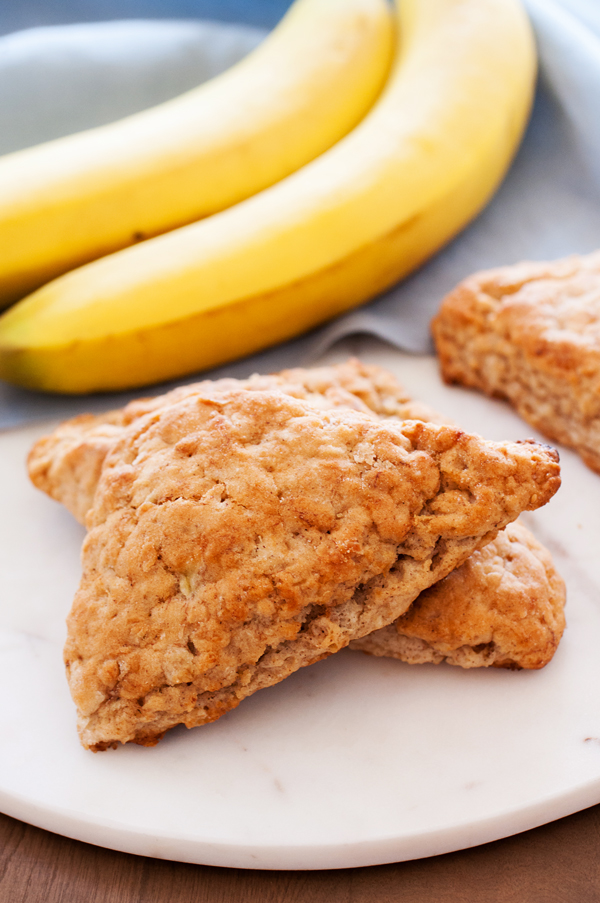 Banana oat scones on serving dish with bananas in the background. 