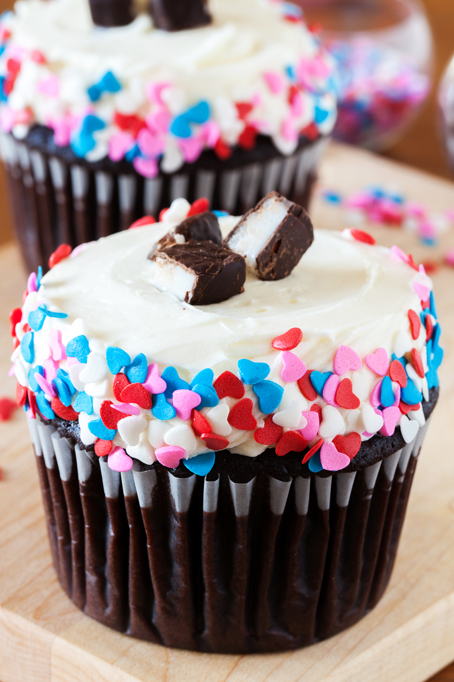 Close-up of two chocolate cupcakes with peppermint frosting and heart sprinkles.