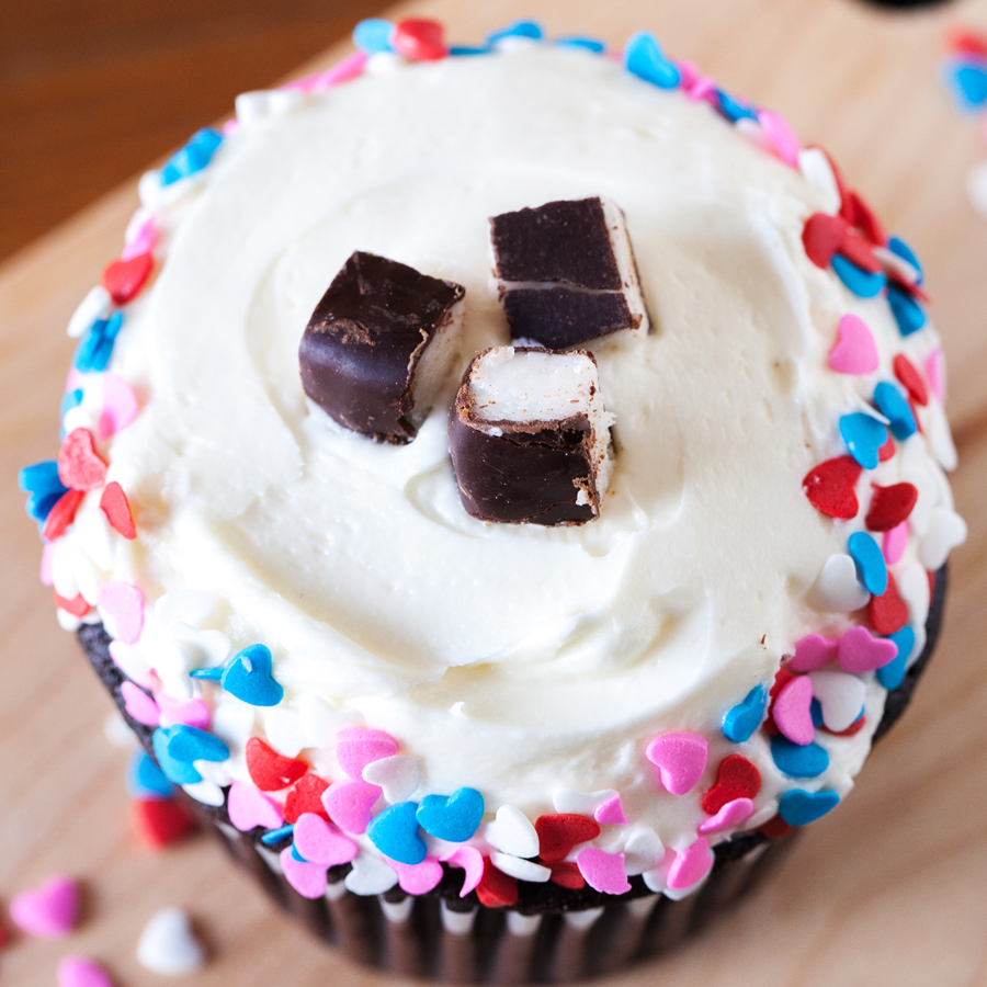 Close-up of a chocolate cupcake with peppermint frosting and heart sprinkles.