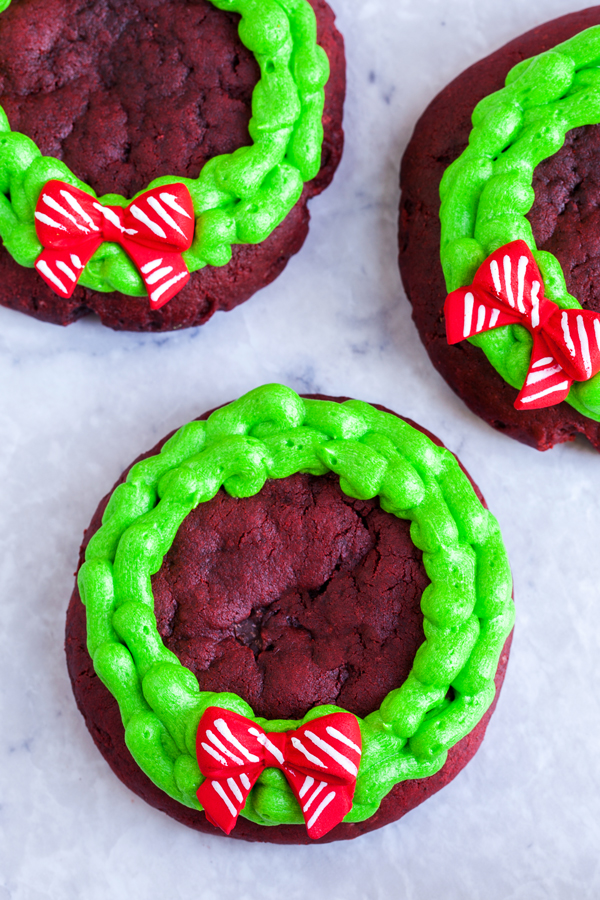Chocolatey and buttery, these Lofthouse Style Red Velvet Wreath Cookies with cream cheese frosting will disappear at your next holiday party or cookie swap!