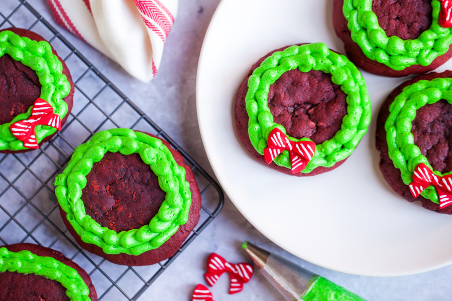 Chocolatey and buttery, these Lofthouse Style Red Velvet Wreath Cookies with cream cheese frosting will disappear at your next holiday party or cookie swap!