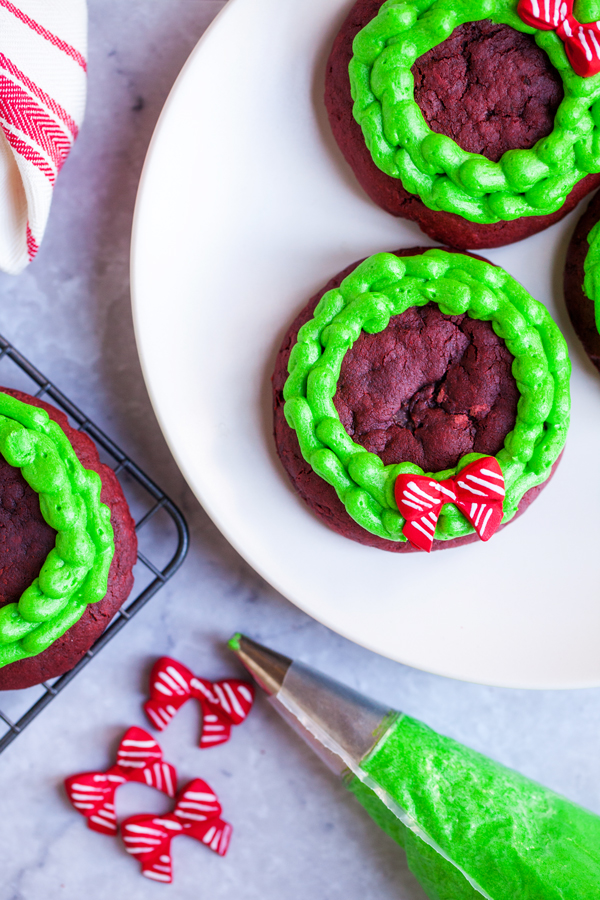 Chocolatey and buttery, these Lofthouse Style Red Velvet Wreath Cookies with cream cheese frosting will disappear at your next holiday party or cookie swap!