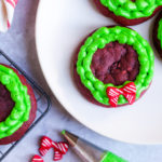 Chocolatey and buttery, these Lofthouse Style Red Velvet Wreath Cookies with cream cheese frosting will disappear at your next holiday party or cookie swap!