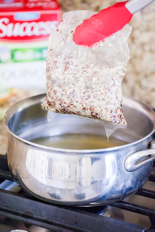 Bagged quinoa being pulled out of a pot with tongs. 