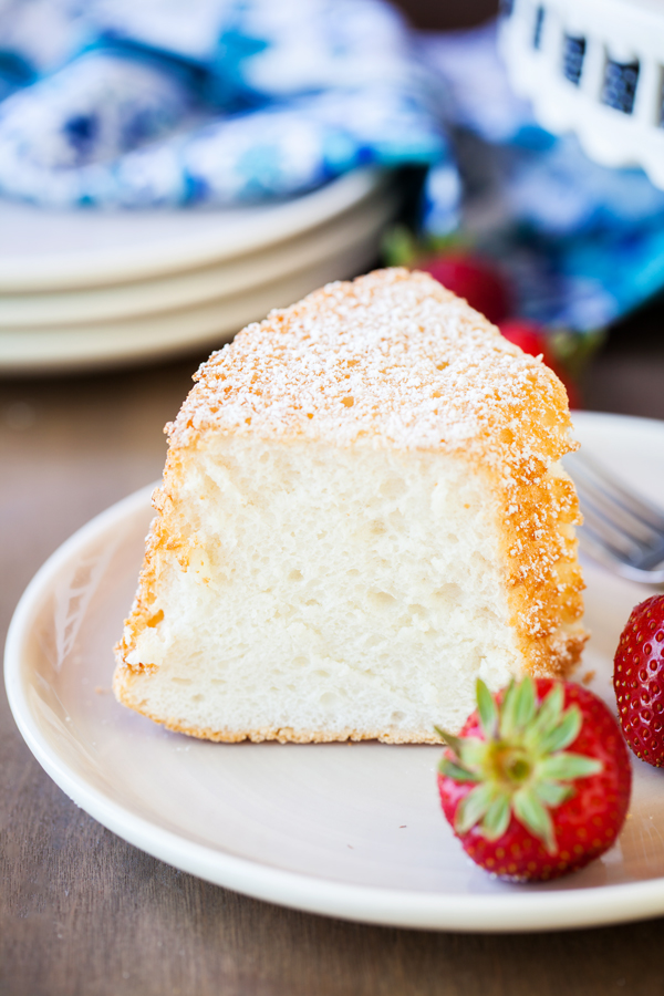 Slice of angel food cake on a plate with fresh strawberries.  