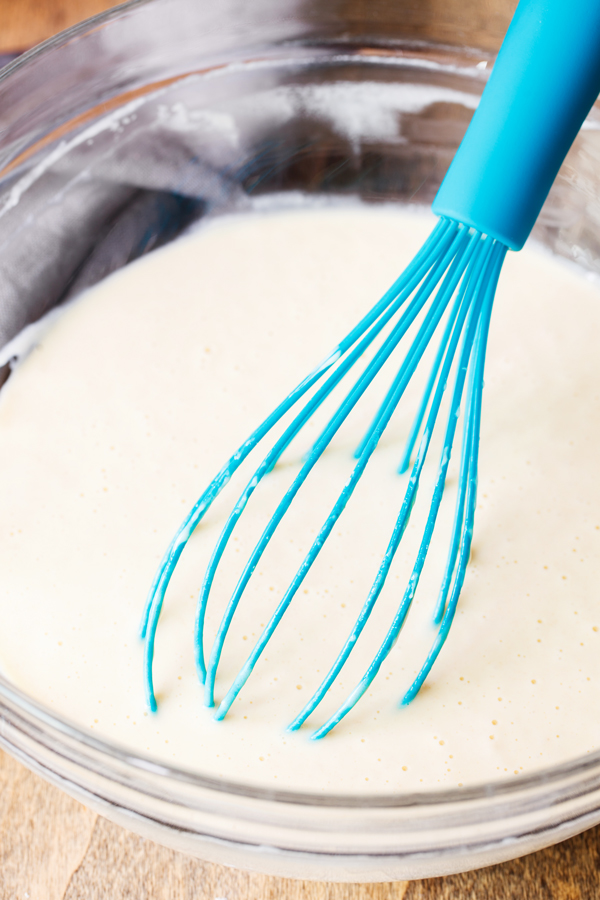 Yeast waffle batter in bowl with whisk. 
