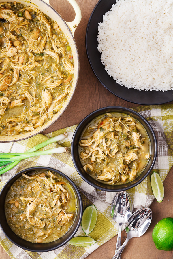 Birds-eye view of white chicken chili in a large pot, two bowls of white chicken chili, and a plate of rice.