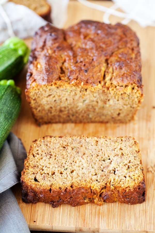 One slice of zucchini bread and loaf in the background. 