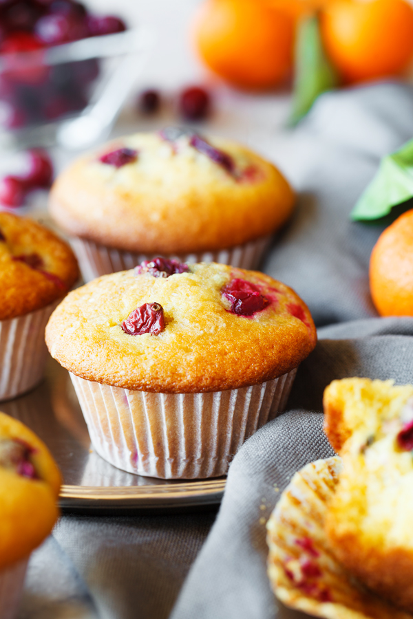 Tangerine cranberry muffins with fresh cranberries and tangerines in the background.