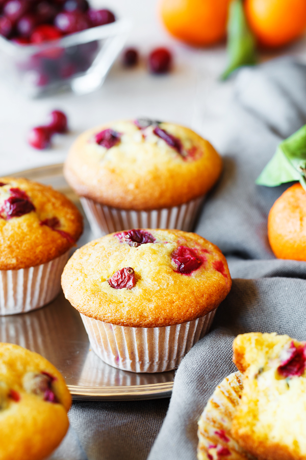 Tangerine cranberry muffins with fresh cranberries and tangerines in the background.