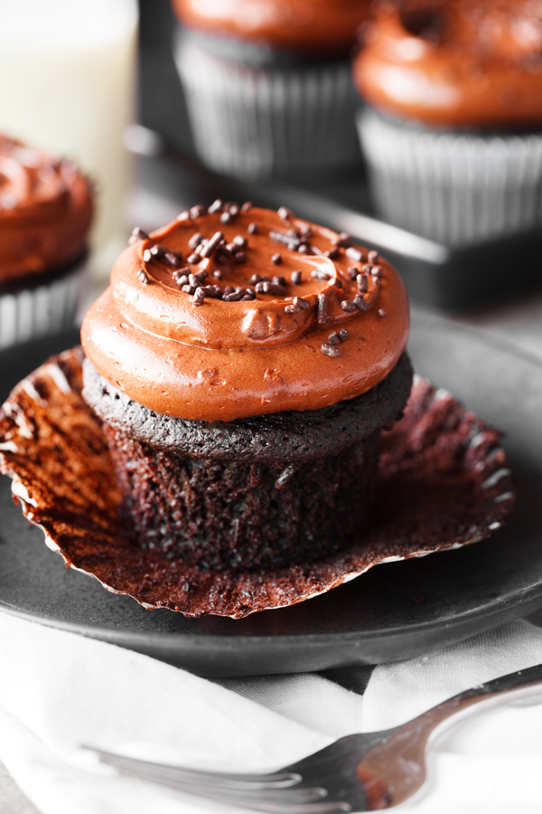 Chocolate cupcake with chocolate frosting and liner peeled off. 