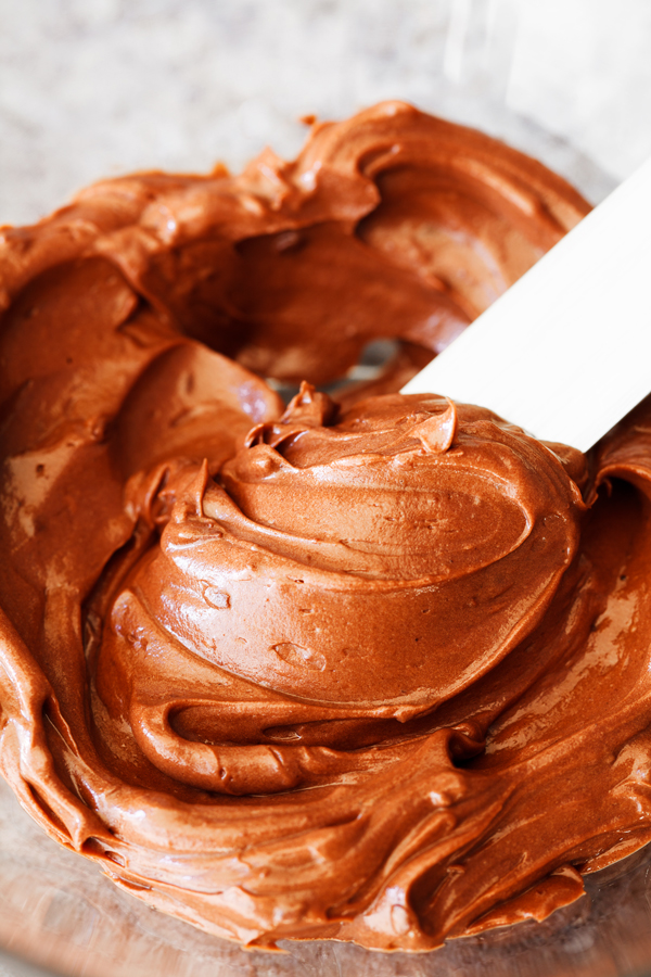 Bowl with chocolate frosting on spatula.