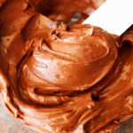 Bowl with chocolate frosting on spatula.