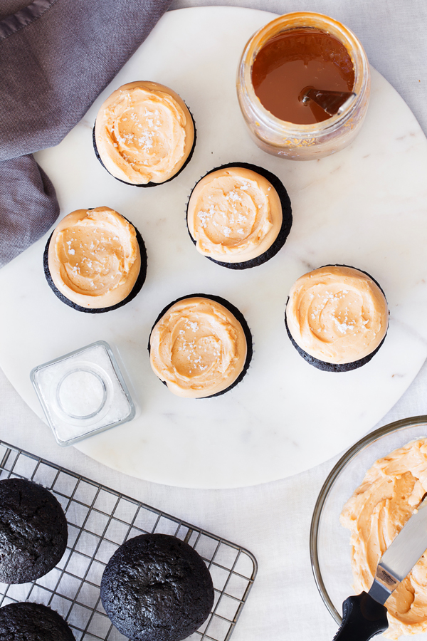 Birds-eye view of chocolate cupcakes on a cooling rack and dulce de leche frosted chocolate cupcakes. 