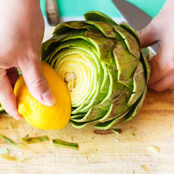 Rubbing of a lemon onto the top of a cut artichoke. 