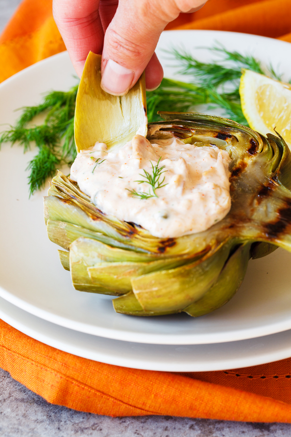 Artichoke leaf being dipped into a tuna salad.