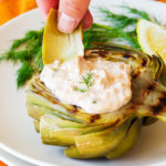 Artichoke leaf being dipped into a tuna salad.