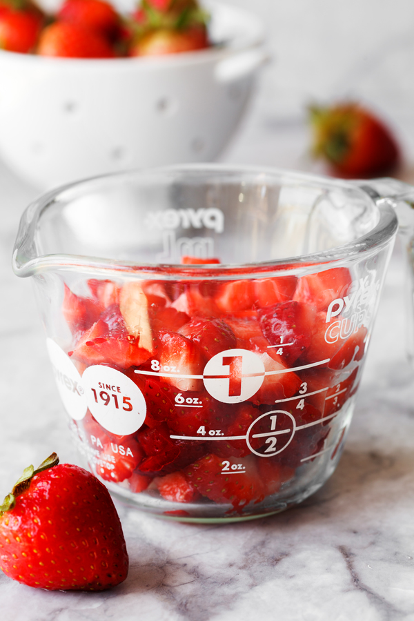 Diced fresh strawberries in a glass measuring cup. 
