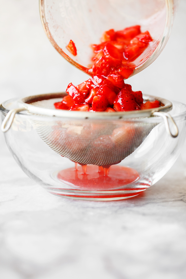 Diced fresh strawberries being drained into a bowl. 