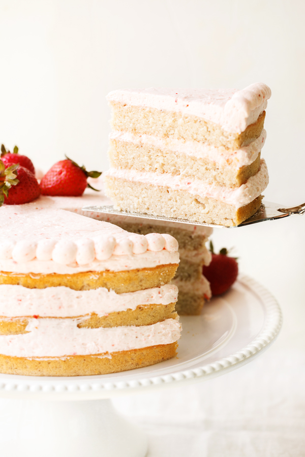 Slice of fresh strawberry cake being lifted out of whole cake.