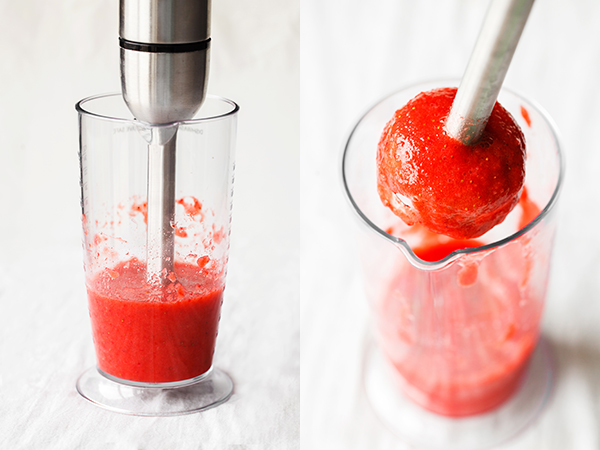 Immersion blender in a cup with strawberry puree