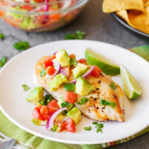 Chicken with avocado salsa on a plate.