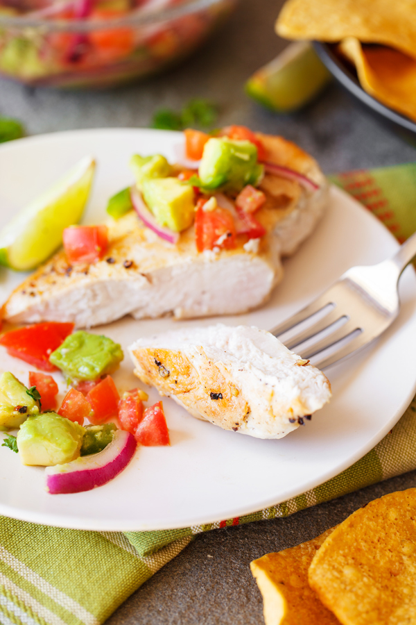 Cut chicken breast fillet on fork for chicken with avocado salsa.
