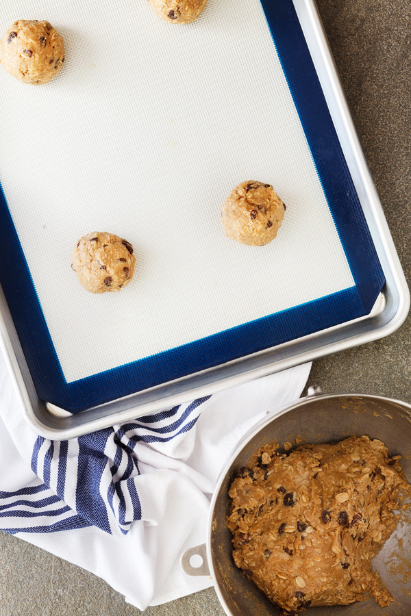 Preparation step for thick and chewy oatmeal raisin cookies - dough balls on cookie sheet.