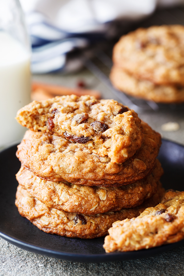 Half eaten cookie on top of a stack of thick and chewy oatmeal and raisin cookies.