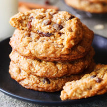 Half eaten cookie on top of a stack of thick and chewy oatmeal and raisin cookies.