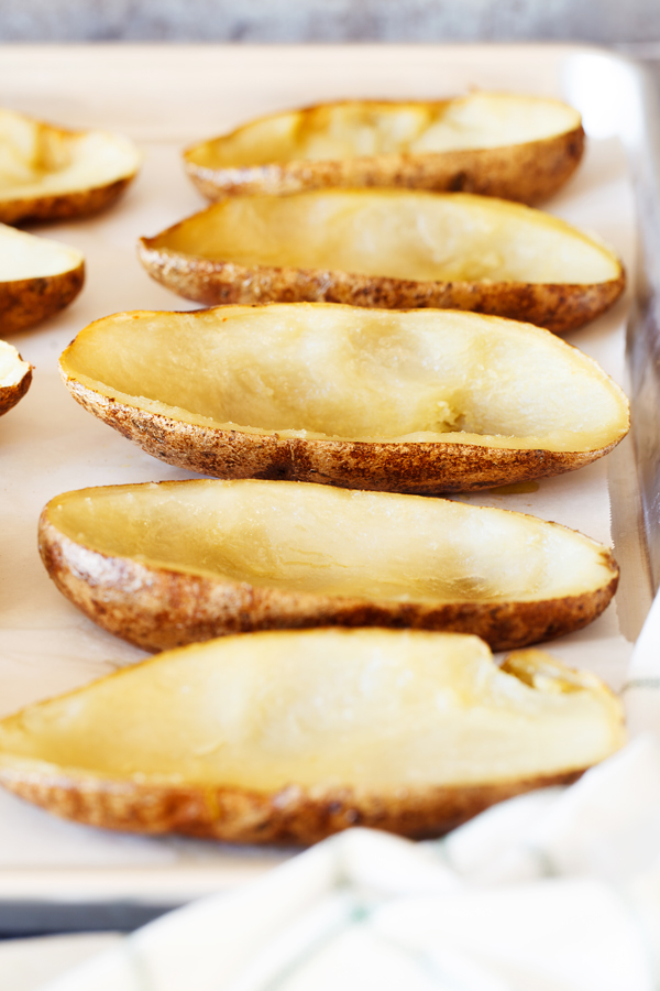 Preparation step for Cheesy Bacon Garlic Stuffed Potato Skins - Hollowed out potato skins on a baking sheet