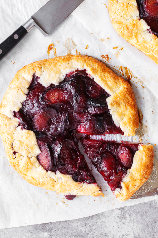Flatlay of plum crostata with slice cut out. 
