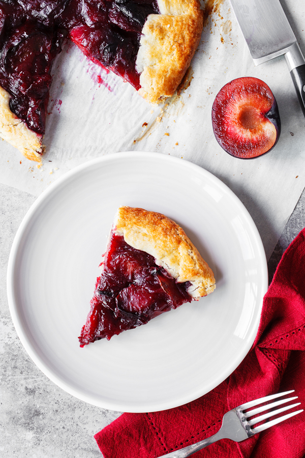 Flatlay of slice of plum crostata on plate.