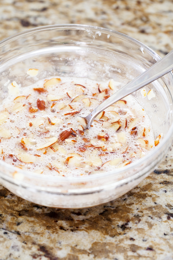 Preparation step for Swedish Visiting Cake Bars - almond and egg whites in a bowl with a fork.