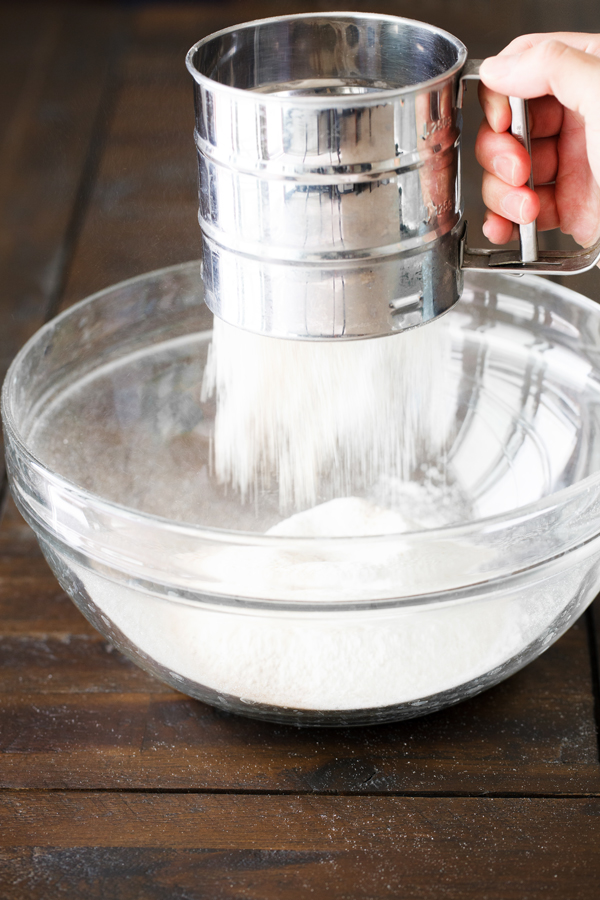 Preparation step for pumpkin spice cupcakes - flour being sifted into a bowl.