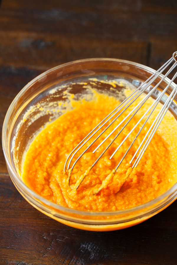 Preparation step for pumpkin spice cupcakes - pumpkin and wet ingredients with whisk in a bowl.