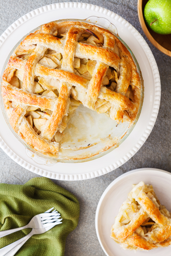 Flat lay of whole classic apple pie with slice removed.