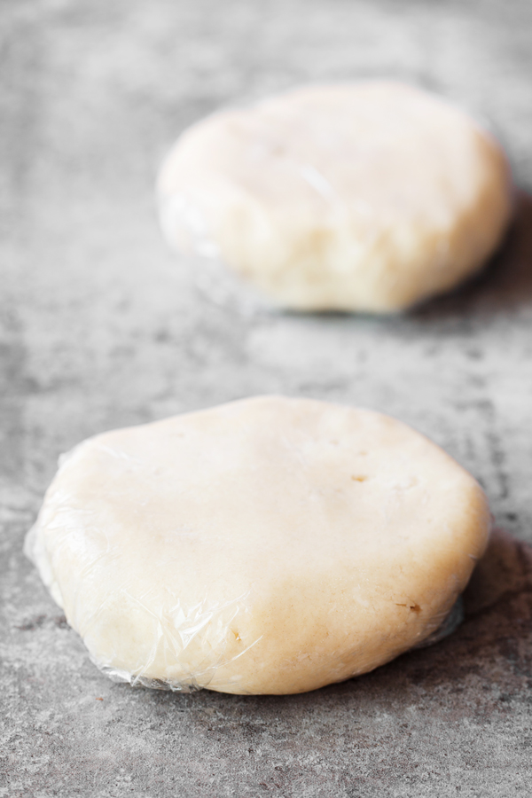 Preparation step for flakey all-butter pie crust - pie dough discs wrapped in plastic