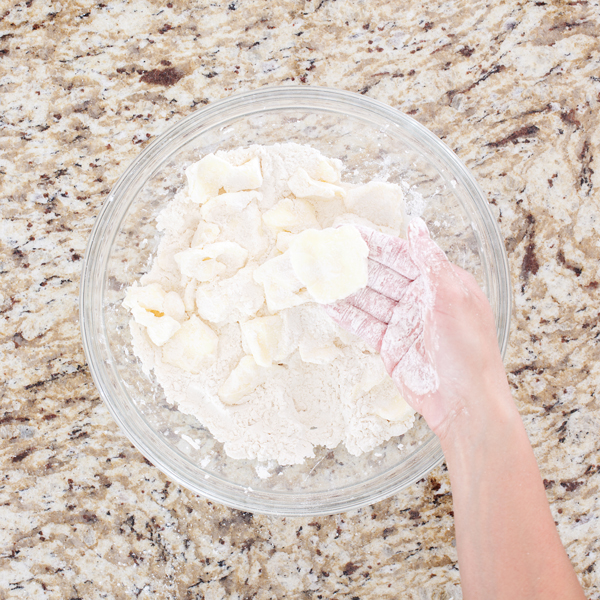 Preparation step for flakey all-butter pie crust - Hands flattening cubes of flour
