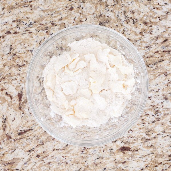 Preparation step for flakey all-butter pie crust - flattened butter cubes in bowl with flour