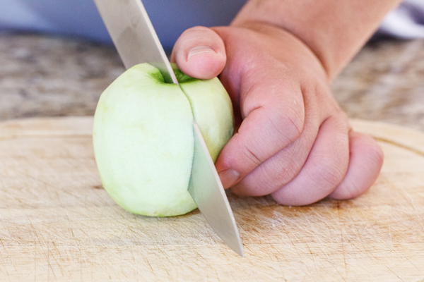 Peeled apple being cut in half.