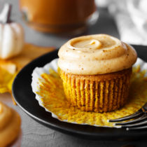 Pumpkin spice latte cupcake with liner removed on a plate.