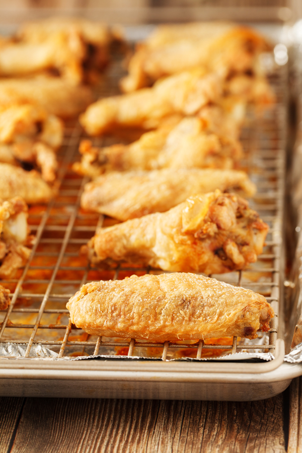 Preparation step for baked buffalo wings - cooked wings on baking rack.