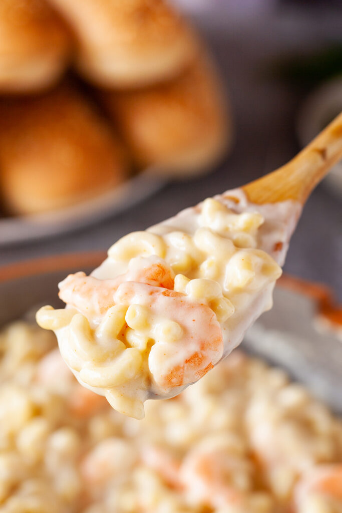Close-up view of shrimp macaroni and cheese on wooden spoon. 